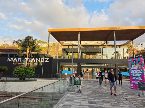 Entrada principal del centro comercial Martiánez en el Puerto de la Cruz con personas paseando al atardecer.