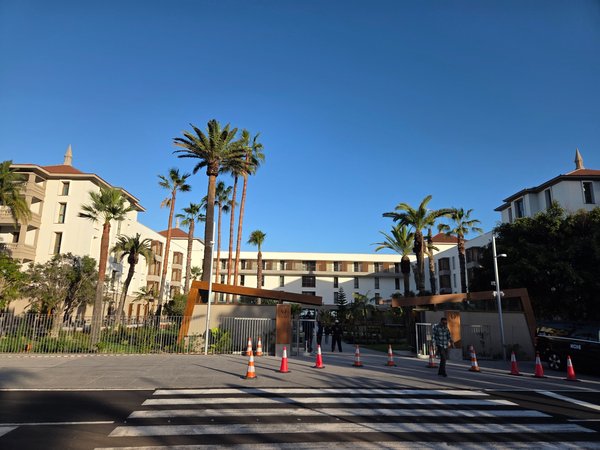 Entrada principal del Gran Hotel Taoro en Puerto de la Cruz, con palmeras, edificios históricos restaurados y acceso vallado frente a la calle.