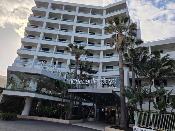 Hotel H10 Tenerife Playa en Puerto de la Cruz, edificio moderno junto a palmeras y acceso principal con terrazas.