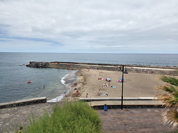 Playa de Bajamar con arena oscura y bañistas disfrutando del mar en un entorno tranquilo.