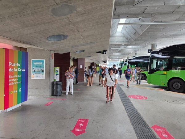 Estación de guaguas TITSA en Puerto de la Cruz con autobuses verdes y viajeros esperando su salida.